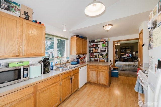 kitchen featuring light countertops, vaulted ceiling, a sink, white appliances, and light wood-type flooring