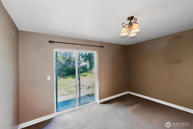 spare room featuring baseboards, a chandelier, and carpet