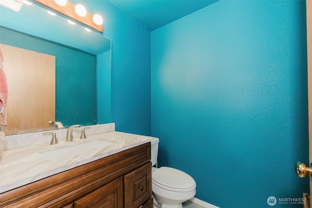bathroom with toilet, vanity, and baseboards