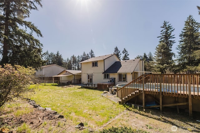 rear view of house featuring fence, a wooden deck, a lawn, a hot tub, and stairway