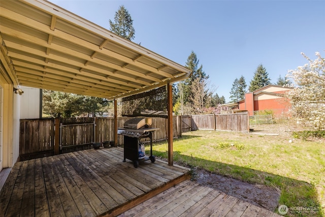 wooden deck featuring grilling area, a lawn, and a fenced backyard