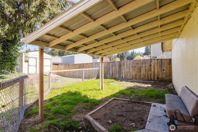 view of yard with a shed, an outbuilding, a vegetable garden, and a fenced backyard