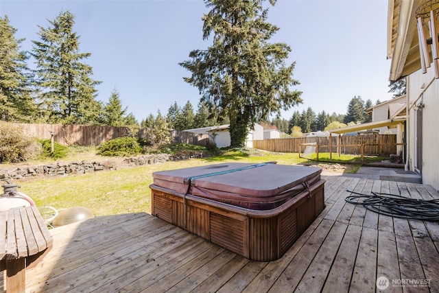 deck with a fenced backyard, a yard, and a covered hot tub