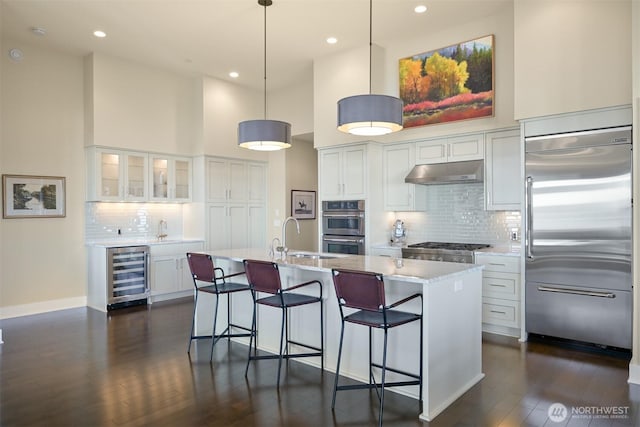 9535 Semiahmoo Pkwy Unit B305, Blaine, WA 98230 - kitchen with white cabinets, appliances with stainless steel finishes, under cabinet range hood, beverage cooler, and a high ceiling