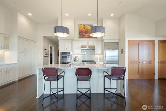 9535 Semiahmoo Pkwy Unit B305, Blaine, WA 98230 - kitchen with high vaulted ceiling, under cabinet range hood, appliances with stainless steel finishes, and white cabinets
