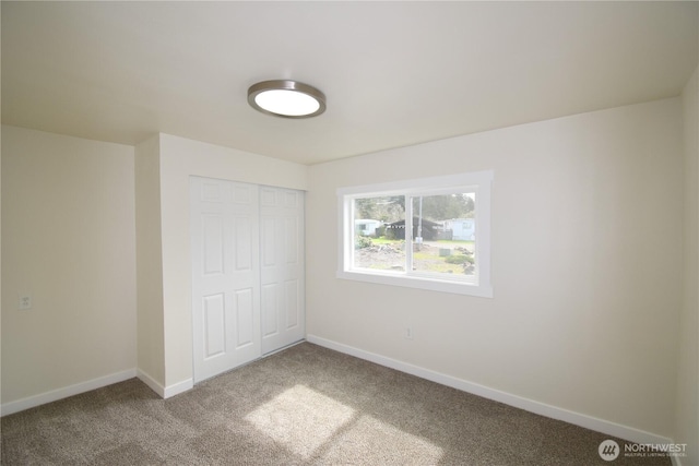 unfurnished bedroom featuring baseboards, carpet floors, and a closet