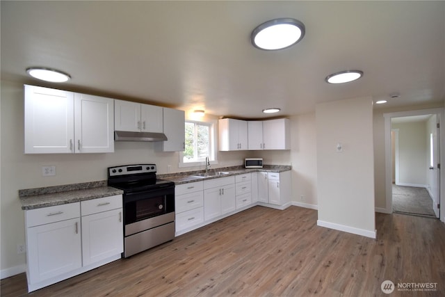 kitchen featuring white cabinets, under cabinet range hood, a sink, white microwave, and stainless steel electric stove