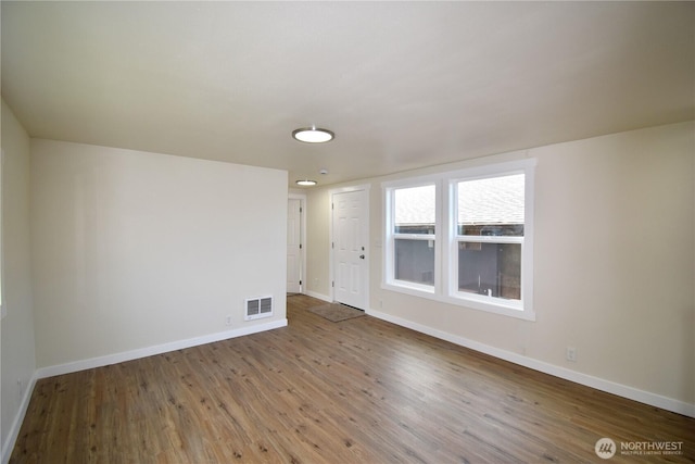 spare room featuring wood finished floors, baseboards, and visible vents