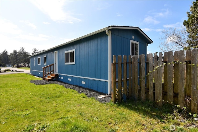 view of side of home with a lawn, fence, and entry steps