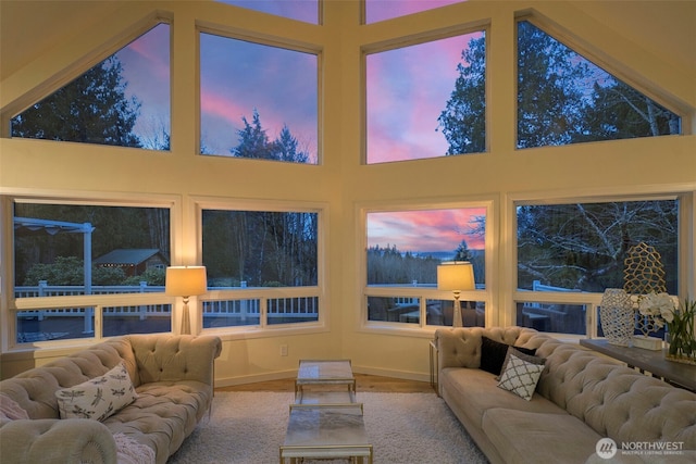 living area with baseboards and a towering ceiling