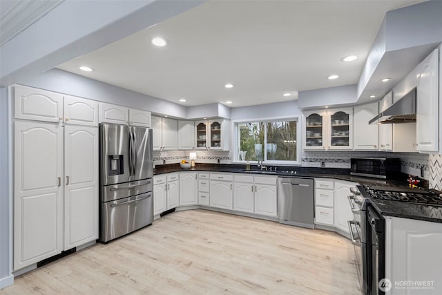 kitchen with tasteful backsplash, light wood-style floors, glass insert cabinets, stainless steel appliances, and exhaust hood