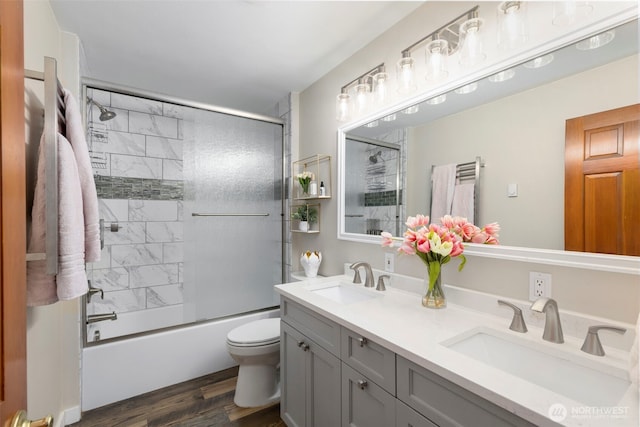 bathroom with toilet, wood finished floors, a sink, and double vanity