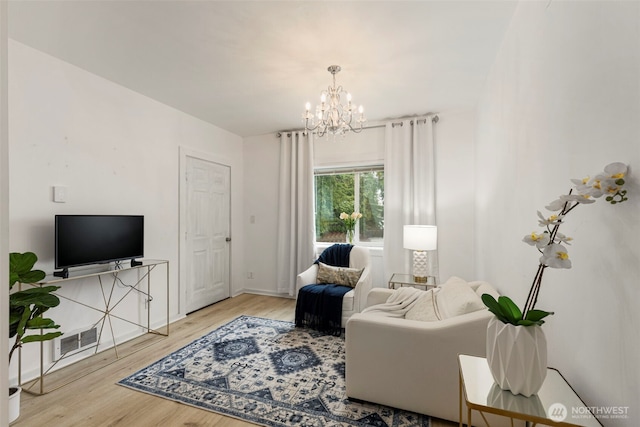 living room featuring a chandelier, wood finished floors, visible vents, and baseboards