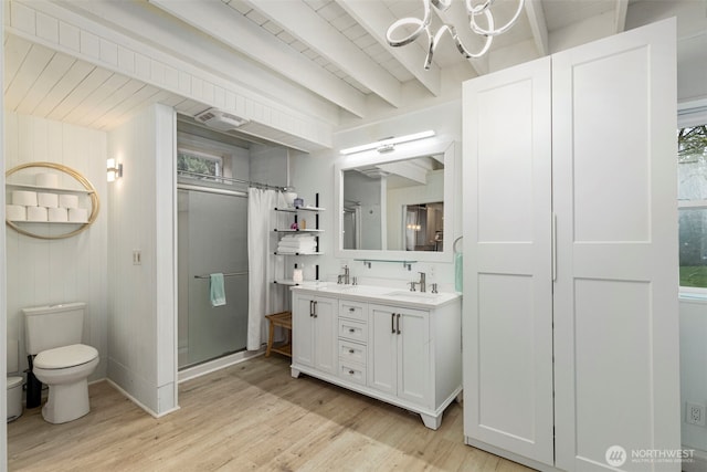 bathroom with wood finished floors, a stall shower, an inviting chandelier, beamed ceiling, and toilet