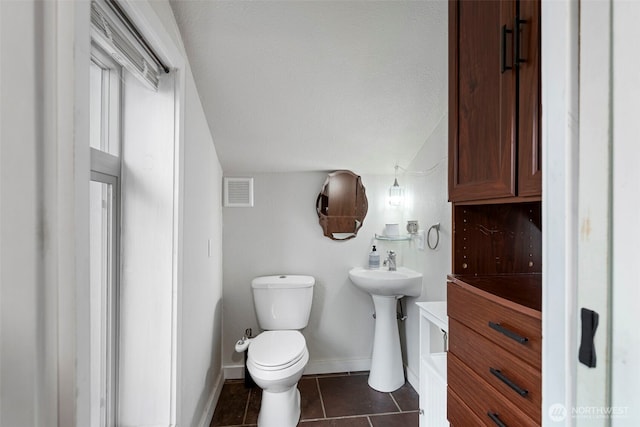 bathroom featuring toilet, tile patterned floors, visible vents, and baseboards