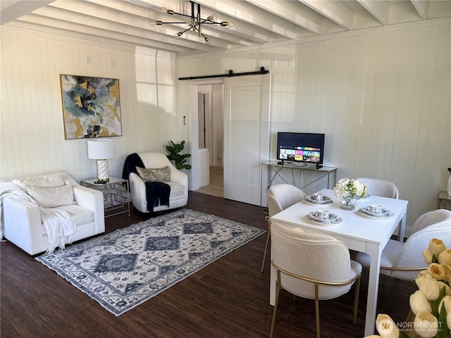 dining area with a barn door, a chandelier, wood finished floors, and beam ceiling