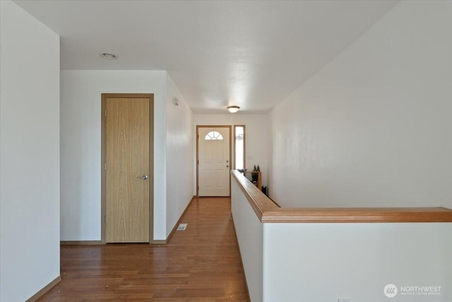 foyer featuring baseboards, visible vents, and wood finished floors