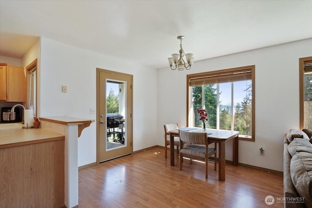 dining area with an inviting chandelier, baseboards, and light wood finished floors