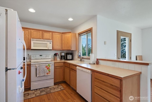 kitchen featuring white appliances, light countertops, a sink, and a peninsula