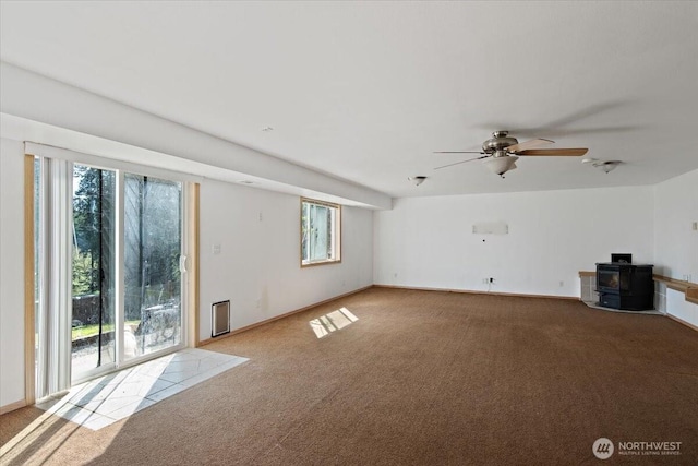 interior space with carpet floors, a wealth of natural light, and a wood stove