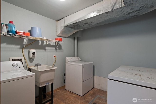 washroom featuring washing machine and clothes dryer, a sink, and laundry area