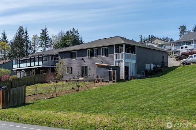 rear view of house with a lawn, fence, and a balcony