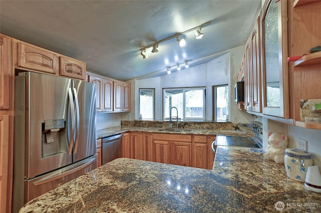 kitchen featuring lofted ceiling, a sink, dark stone counters, and appliances with stainless steel finishes