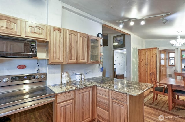 kitchen with stainless steel electric range oven, black microwave, stone countertops, and a peninsula
