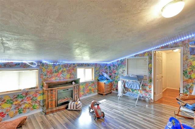 game room featuring vaulted ceiling, baseboards, wallpapered walls, and wood finished floors