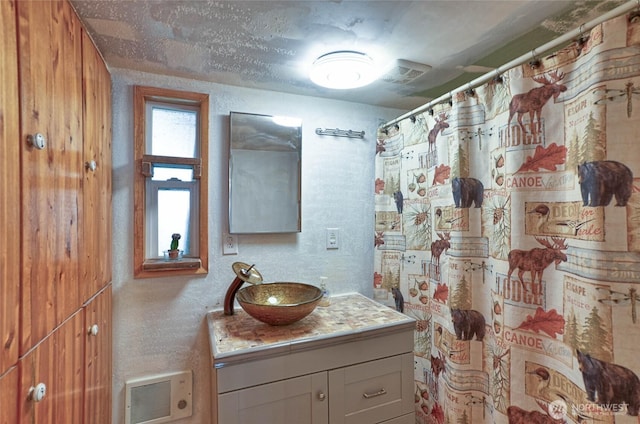 full bathroom featuring a textured wall, vanity, and a shower with curtain