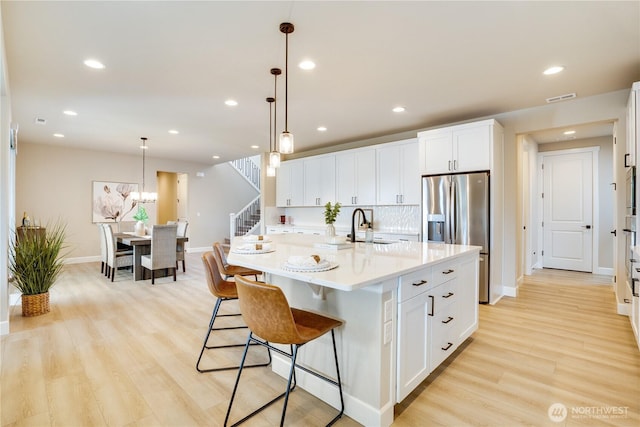 kitchen with stainless steel fridge, baseboards, visible vents, light wood-style floors, and light countertops