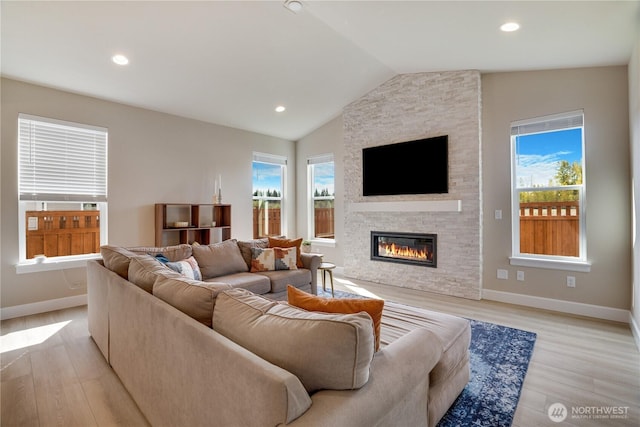 living area with recessed lighting, lofted ceiling, light wood finished floors, baseboards, and a fireplace