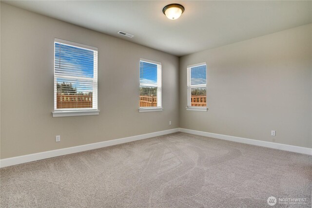 unfurnished room featuring visible vents, baseboards, and light colored carpet