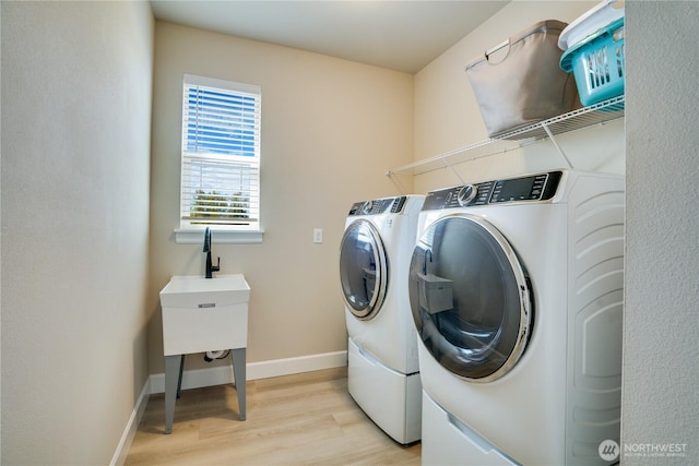 laundry room featuring washing machine and clothes dryer, light wood-style floors, laundry area, and baseboards