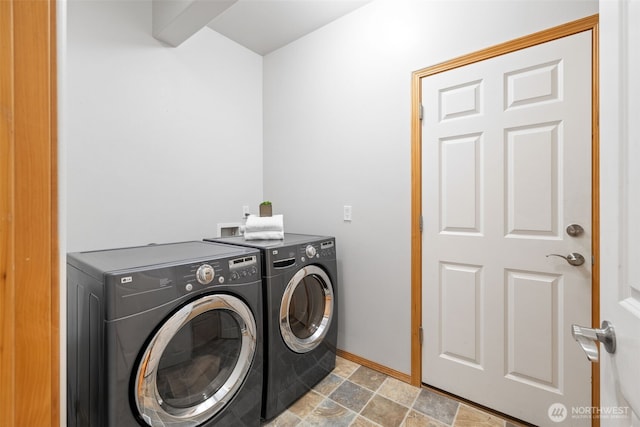 laundry area with stone finish flooring, washing machine and dryer, laundry area, and baseboards