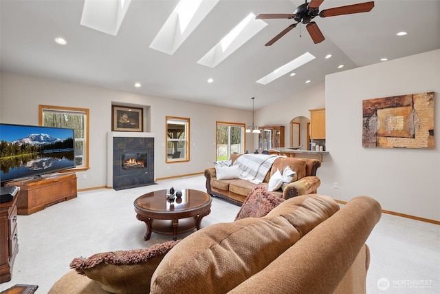 living room featuring light carpet, vaulted ceiling with skylight, and recessed lighting