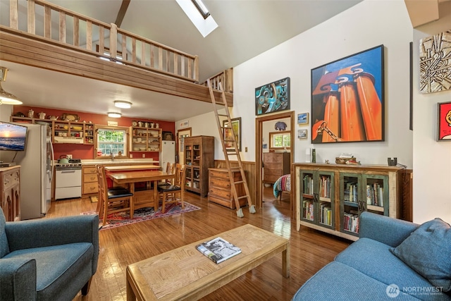 3404 Oysterville Rd, Oysterville, WA 98641 - living area featuring a skylight, high vaulted ceiling, light wood-style floors, and wainscoting