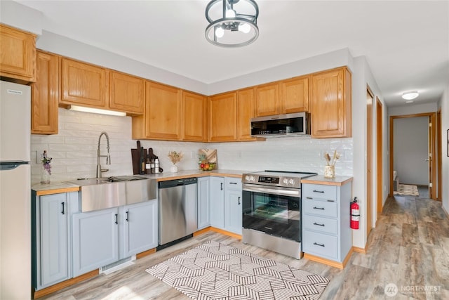 342 N Shore Ct Unit C, Manson, WA 98831 - kitchen featuring stainless steel appliances, a sink, light countertops, light wood-style flooring, and decorative backsplash