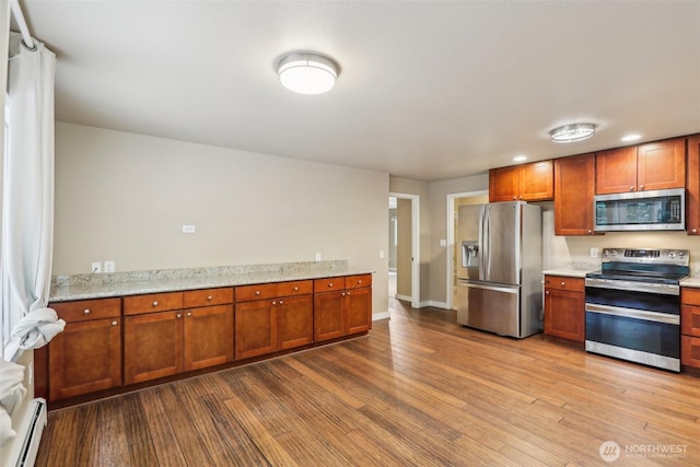 24010 SE 168th St, Issaquah, WA 98027 - kitchen featuring stainless steel appliances, a baseboard heating unit, wood finished floors, light stone countertops, and baseboards