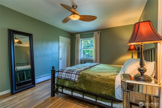 bedroom with baseboards, ceiling fan, wood finished floors, and a baseboard heating unit