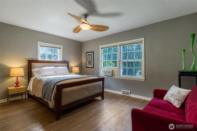 bedroom with a ceiling fan, wood finished floors, baseboards, and visible vents