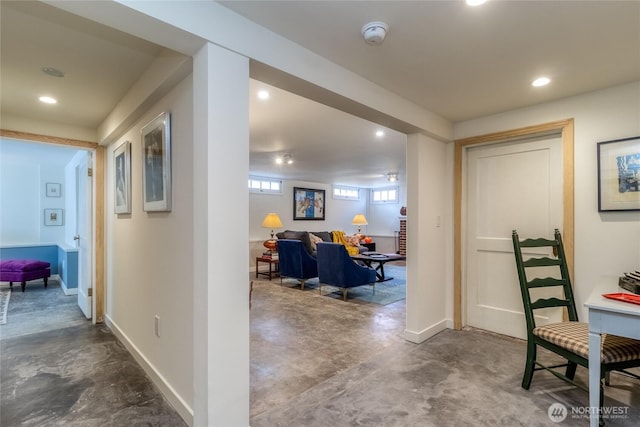 hallway featuring baseboards, concrete floors, and recessed lighting
