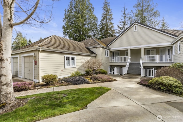 view of front of home featuring covered porch, a tile roof, a garage, and stairway