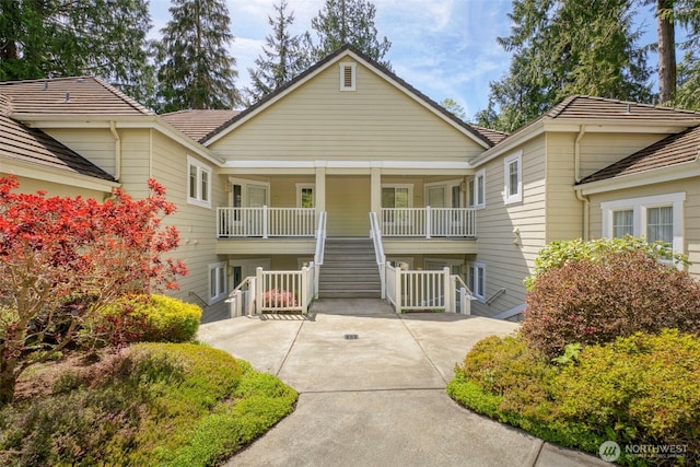 view of front of home with covered porch, stairway, and a tiled roof