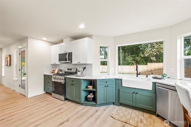 19713 17th St SW, Lakebay, WA 98349 - kitchen featuring appliances with stainless steel finishes, a sink, light wood-style flooring, tasteful backsplash, and light countertops