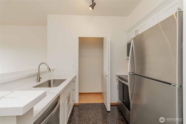 668S Lane St Unit 702, Seattle, WA 98104 - kitchen featuring a sink, granite finish floor, light stone countertops, stainless steel appliances, and white cabinets