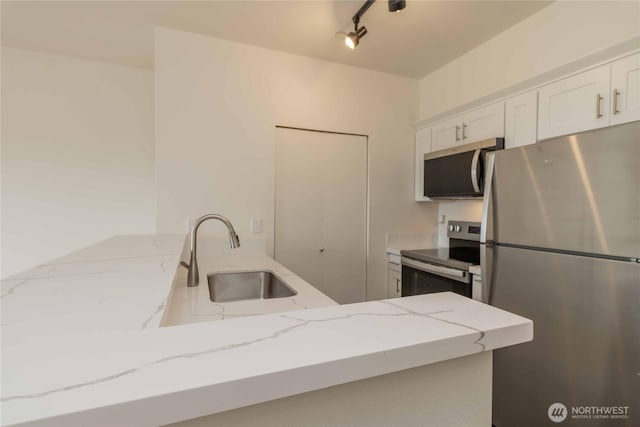 668S Lane St Unit 702, Seattle, WA 98104 - kitchen with white cabinets, track lighting, stainless steel appliances, a sink, and light stone counters