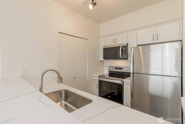 668S Lane St Unit 702, Seattle, WA 98104 - kitchen with white cabinetry, light stone countertops, a sink, and stainless steel appliances