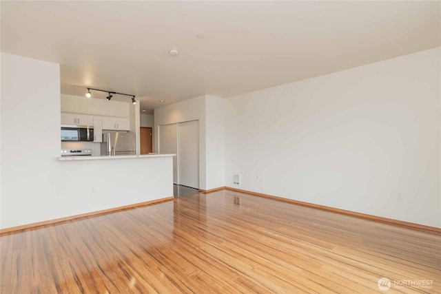 668S Lane St Unit 702, Seattle, WA 98104 - unfurnished living room featuring light wood finished floors, baseboards, and rail lighting
