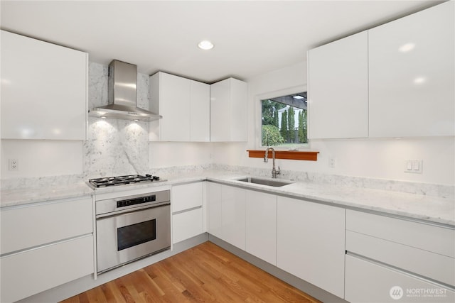 3754 SW 107th St, Seattle, WA 98146 - kitchen featuring stainless steel appliances, wall chimney range hood, a sink, modern cabinets, and white cabinetry